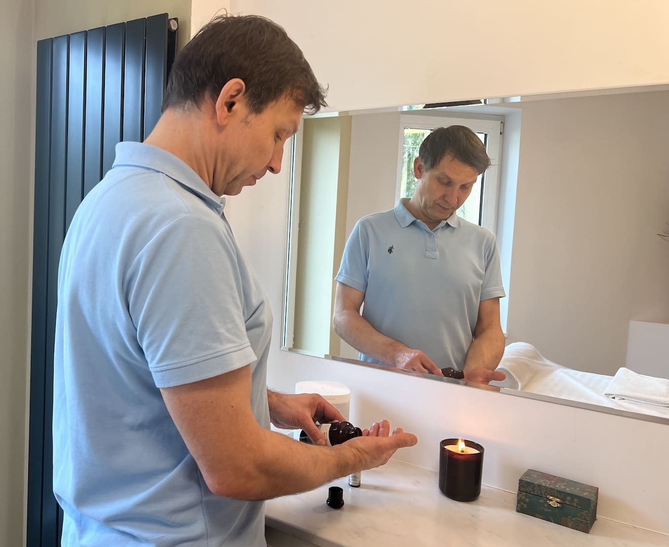 Osteopata Dawid Kujawiński przygotowuje się do sesji osteopatycznej nalewając na ręce olejek aromatyczny